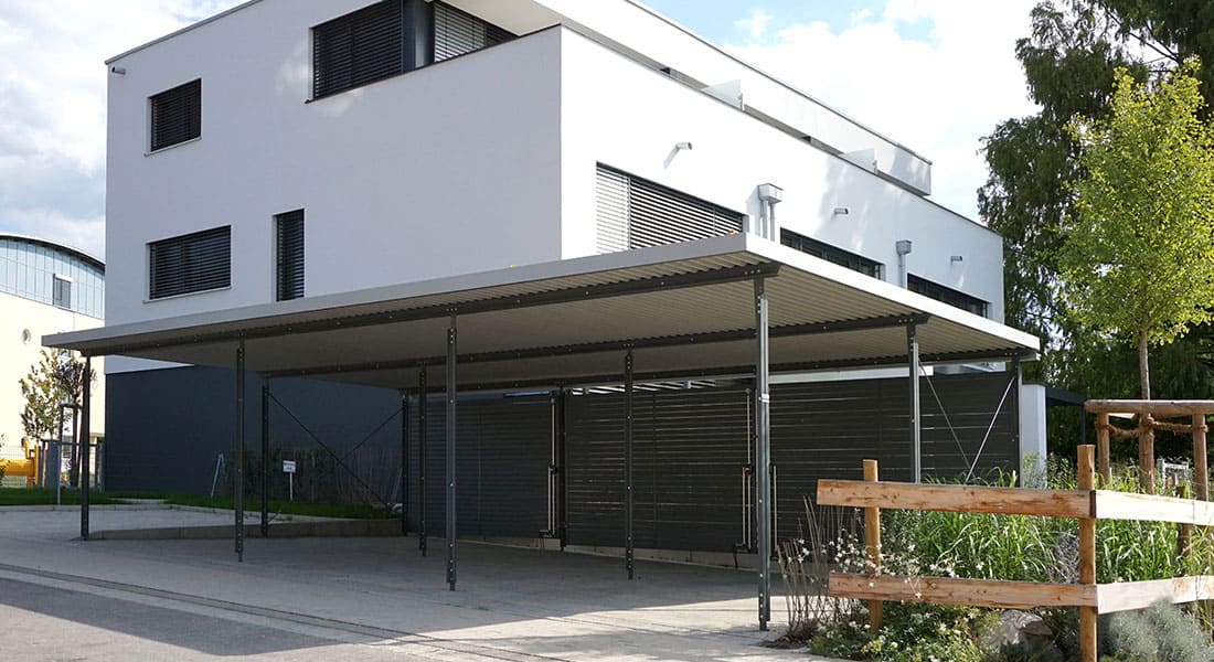 Reihen-Carport mit 3 Stellplätzen, Dach mit extensiver Begrünung und Wandelemente aus Trapezprofil, Lärche vorvergraut