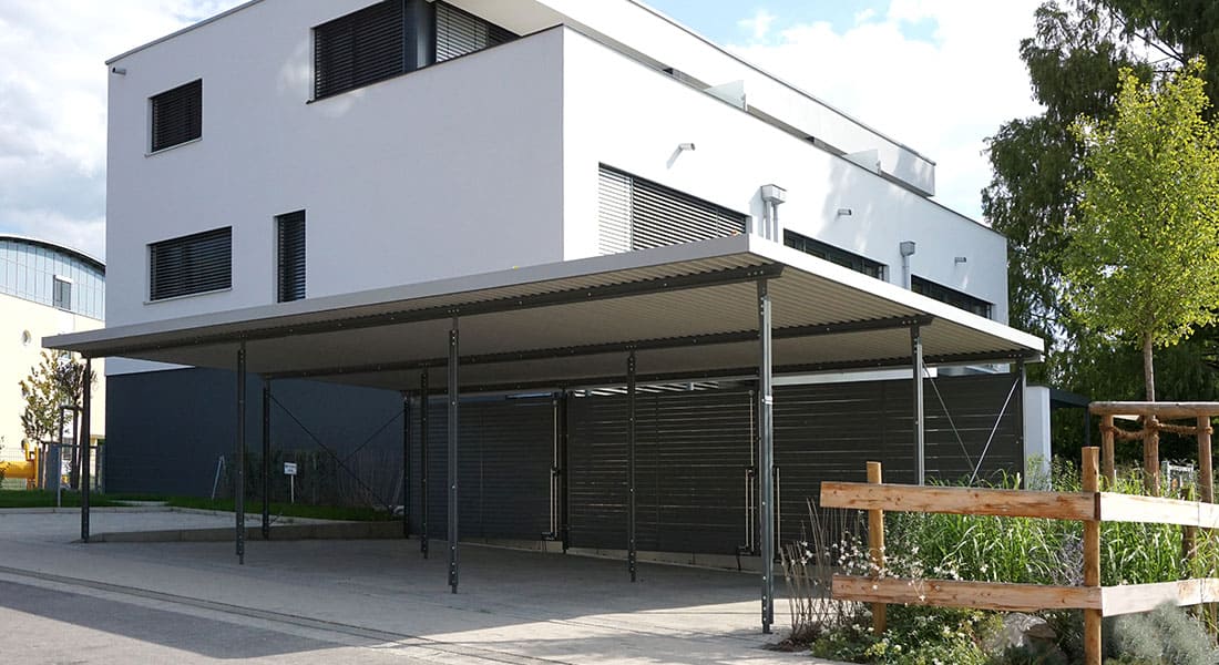 Reihen-Carport mit 3 Stellplätzen, Dach mit extensiver Begrünung und Wandelemente aus Trapezprofil, Lärche vorvergraut